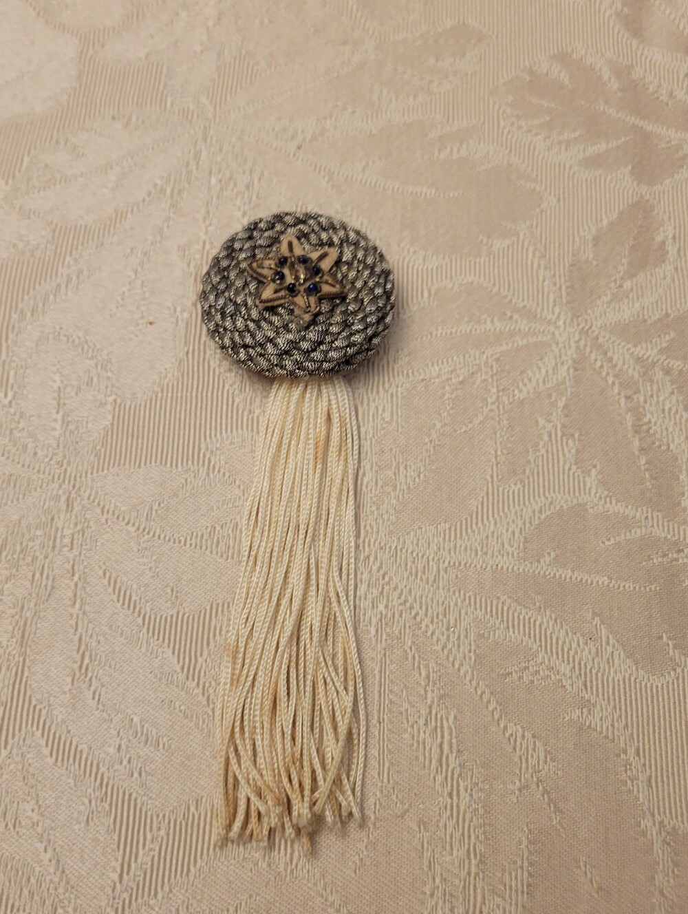 Decorative Silver-Tone Braided Tassel Pin with Cream Fringe